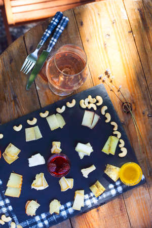 Grape, set of different kind of cheeses with a glass of pink wine on the table in the gardenの写真素材