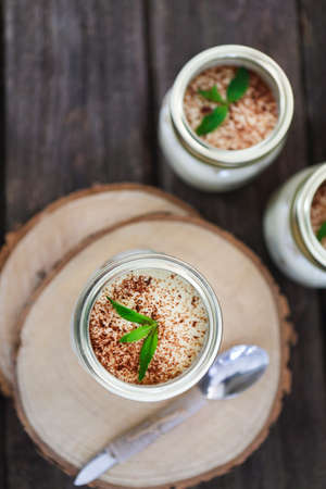 Tiramisu. Three portions on wooden table with mint