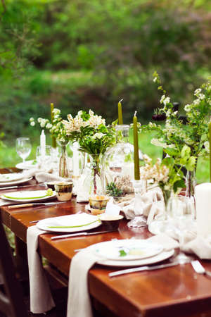 Decoration of wedding table with crystal vases, flowers and branches in botanical style in the gardenの写真素材