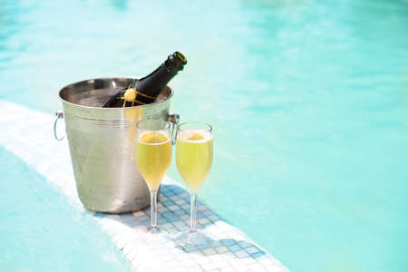 Ice bucket champagne bottle and two glasses near smimming poolの写真素材