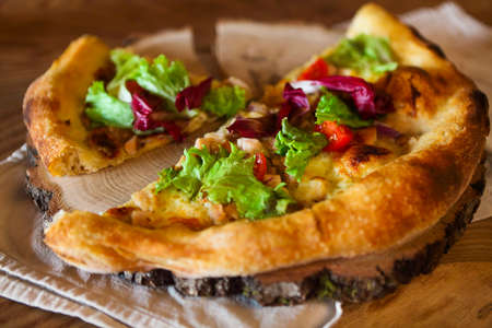 Homemade pizza and vegetables on wooden table in the kitchenの写真素材