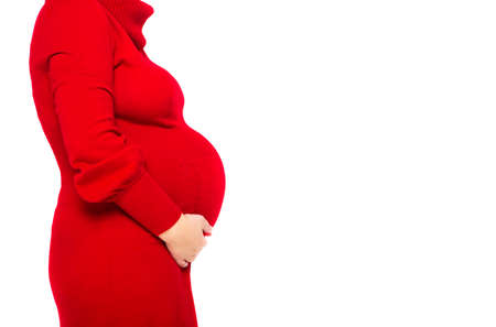 Happy young pregnant woman in red dress touching her belly. Close upの写真素材