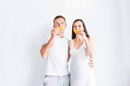 Young smiling pregnant pretty woman and man with fruitの写真素材