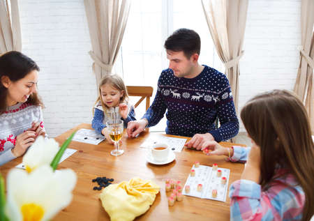 Happy young family plaing board game with two daughtersの写真素材