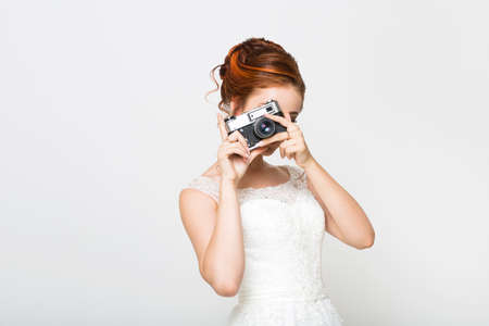 Young pretty bride with photo camera on white backgroundの写真素材