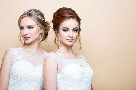 Two young caucasian pretty brides in studio on isolated background