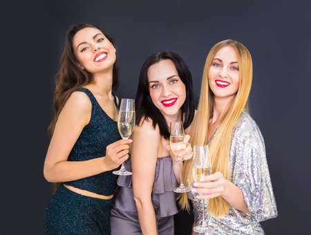 Three young smiling woman having fun an drinking champagne. Celebration and night life conceptの写真素材