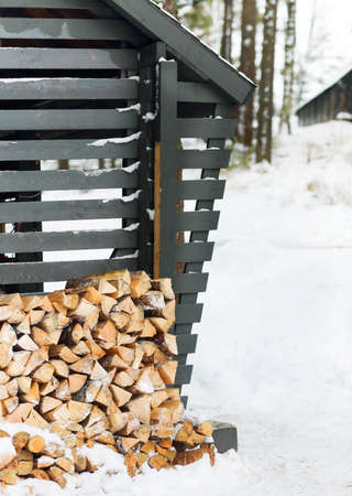 Stack of firewood near the wall of a wooden building in winter timeの写真素材