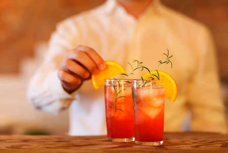 Bartender making two cocktails on wooden bar counterの写真素材