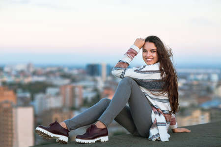 Young woman outdoors on city background in sunny day