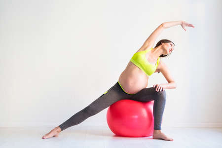 One young pregnant woman doing fitness exercises at studioの写真素材