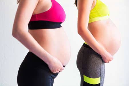 Two young pregnant women doing yoga exercises at studioの写真素材