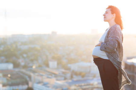 Young happy pregnant woman outdoor autumn day on city backgroundの写真素材
