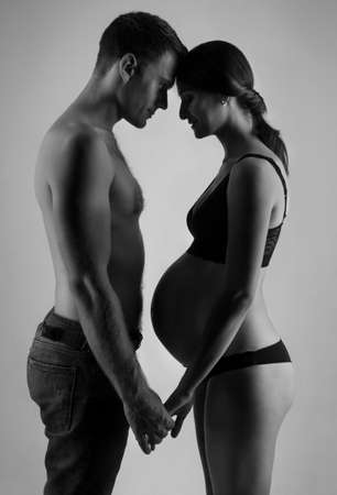 Young man and pregnant woman in studio in lingerieの写真素材