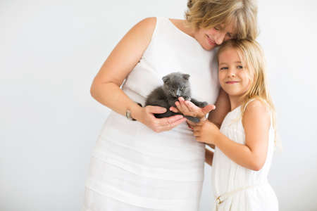 Mature woman embrace with young girl and cat. Grandmother and girl