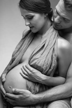 Young man and pregnant woman in studio in lingerieの写真素材