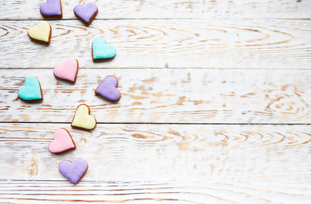 Pink, violet, yellow and green heart cookies on a white wooden background with copy spaceの写真素材