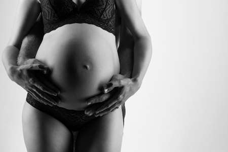 Young man and pregnant woman in studio in lingerieの写真素材
