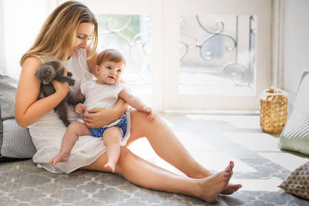 Young pretty woman and baby girl playing indoorsの写真素材