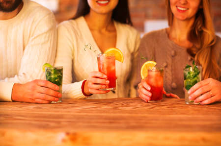 Young men and women drinking cocktail at partyの写真素材