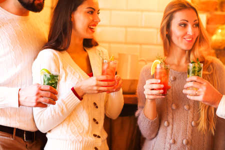 Young men and women drinking cocktail at partyの写真素材