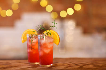Two red cocktail glasses on wooden bar counter