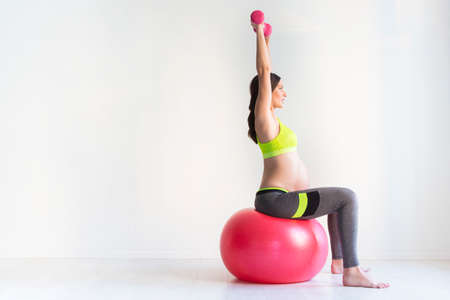 One young pregnant women doing fitness exercises. Healthy living concept