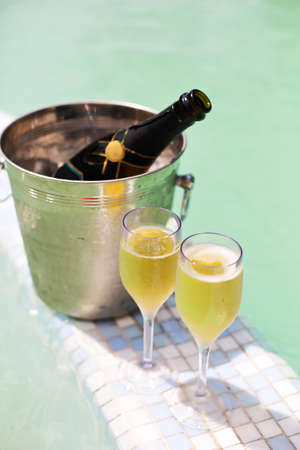 Champagne glasses and bottle in ice bucket near swimming pool. Vacation and romance conceptの写真素材