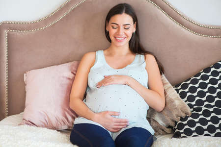 Pregnant woman indoors sitting on the bed