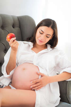 Young pretty pregnant woman sitting on sofa indoors