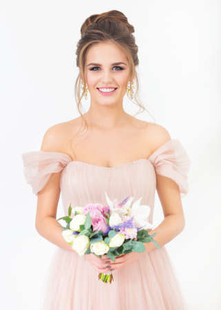 Young pretty bride with bridal bouquet wearing wedding dress indoorsの写真素材