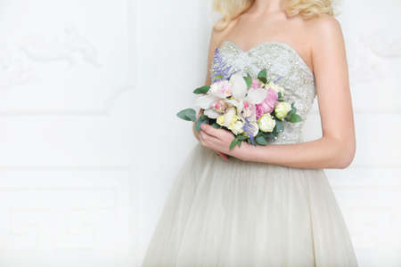 Young pretty bride with bridal bouquet wearing wedding dress indoorsの写真素材