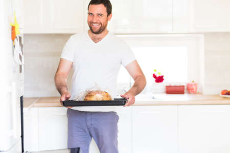 Portrait of a handsome man cooking meat at home in kitchen 