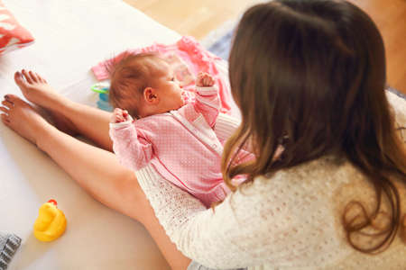 Young mother holding her newborn child. Mom nursing baby. Family at home Close up
