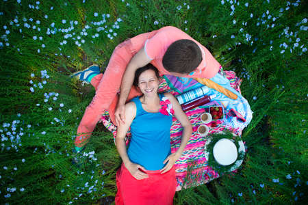 Young happy beautiful pregnant couple in linen field. Top viewの写真素材