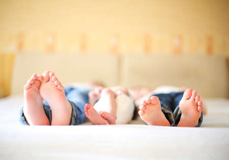 Sweet family in bed. Three sisters, close up on feet. Holiday and happiness conceptの写真素材