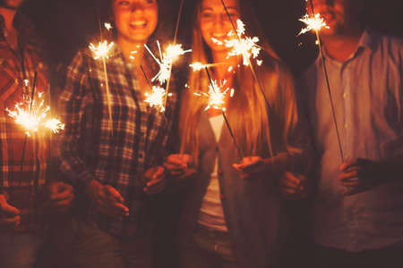 Young happpy people with sparklers having fun on outdoor partyの写真素材