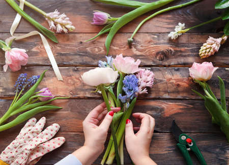 Florist at work. Woman making bouquet of spring flowers on the rustic wooden table