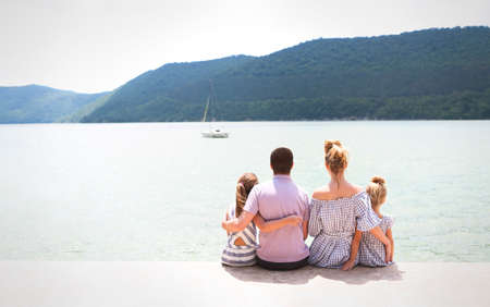 Young family of four sitting by lake. Travel and holiday conceptの写真素材