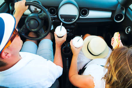 Happy couple driving in car with coffee in they arms. Top viewの写真素材