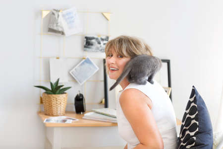 Little grey cat sitting on the sholder of a mature woman 