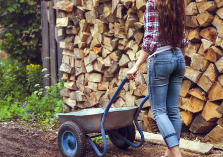 Beautiful youngcountry  woman posing on firewood background の写真素材