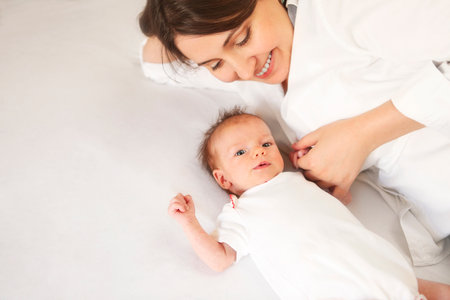 Young mother holding her newborn child. Mom nursing baby. Family at home. Close up
