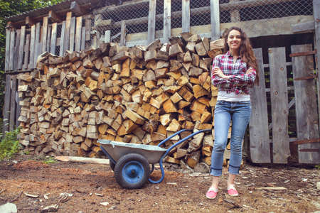 Beautiful youngcountry  woman posing on firewood background の写真素材