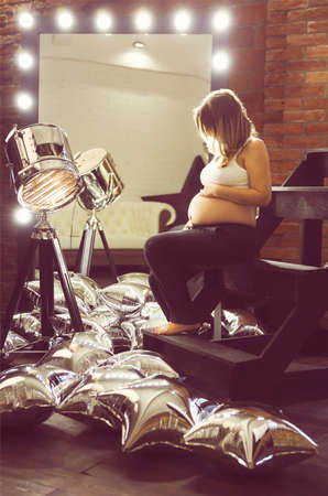 Young pregnant woman posing near the mirror and spotlight の写真素材