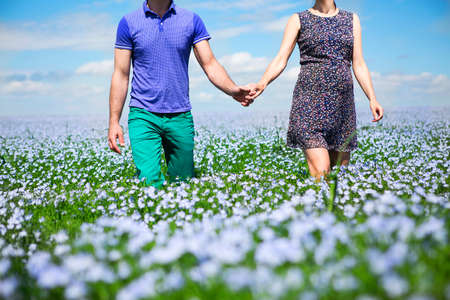 Young happy beautiful pregnant couple  walking in linen fieldの写真素材