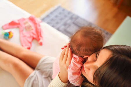 Young mother holding her newborn child. Mom nursing baby. Family at home. Close upの写真素材