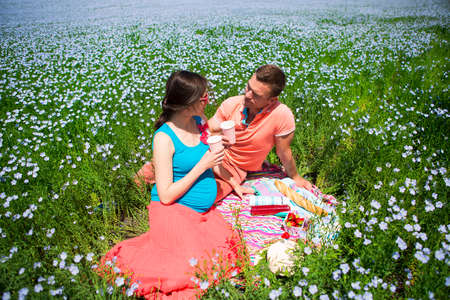 Portrait of a young happy beautiful pregnant couple in linen field