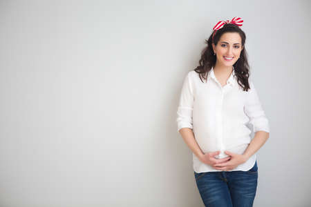 Portrait of the young smiling pregnant woman indoors