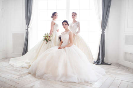 Three young woman with bouquets wearing wedding dressesの写真素材